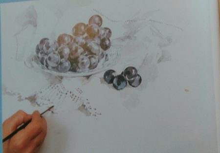 hand with a brush adding details to a watercolor painting of grapes 
