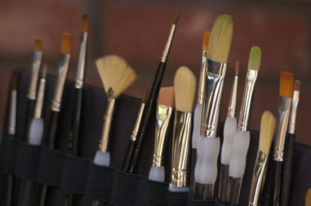 several different paintbrushes in a canvas brush holder