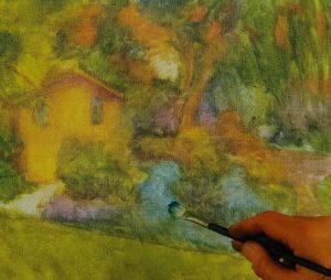 hand with a brush sketching a house with a garden