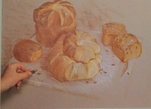 hand adding finishing details to the drawing of pastries made with conte crayons