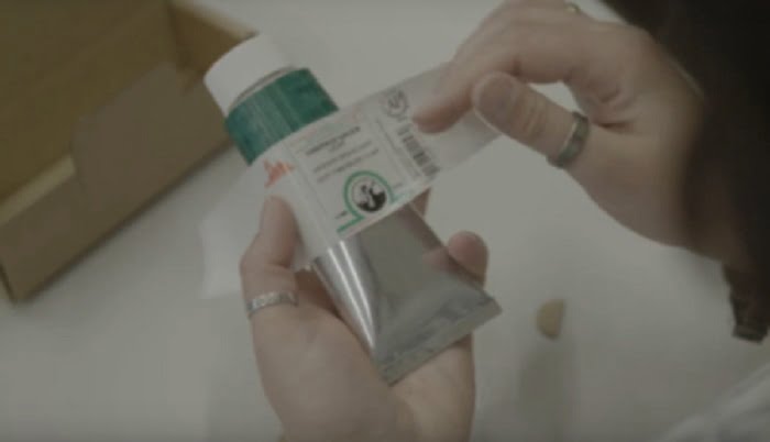 female placing a label on a tube of Old Holland oil paint